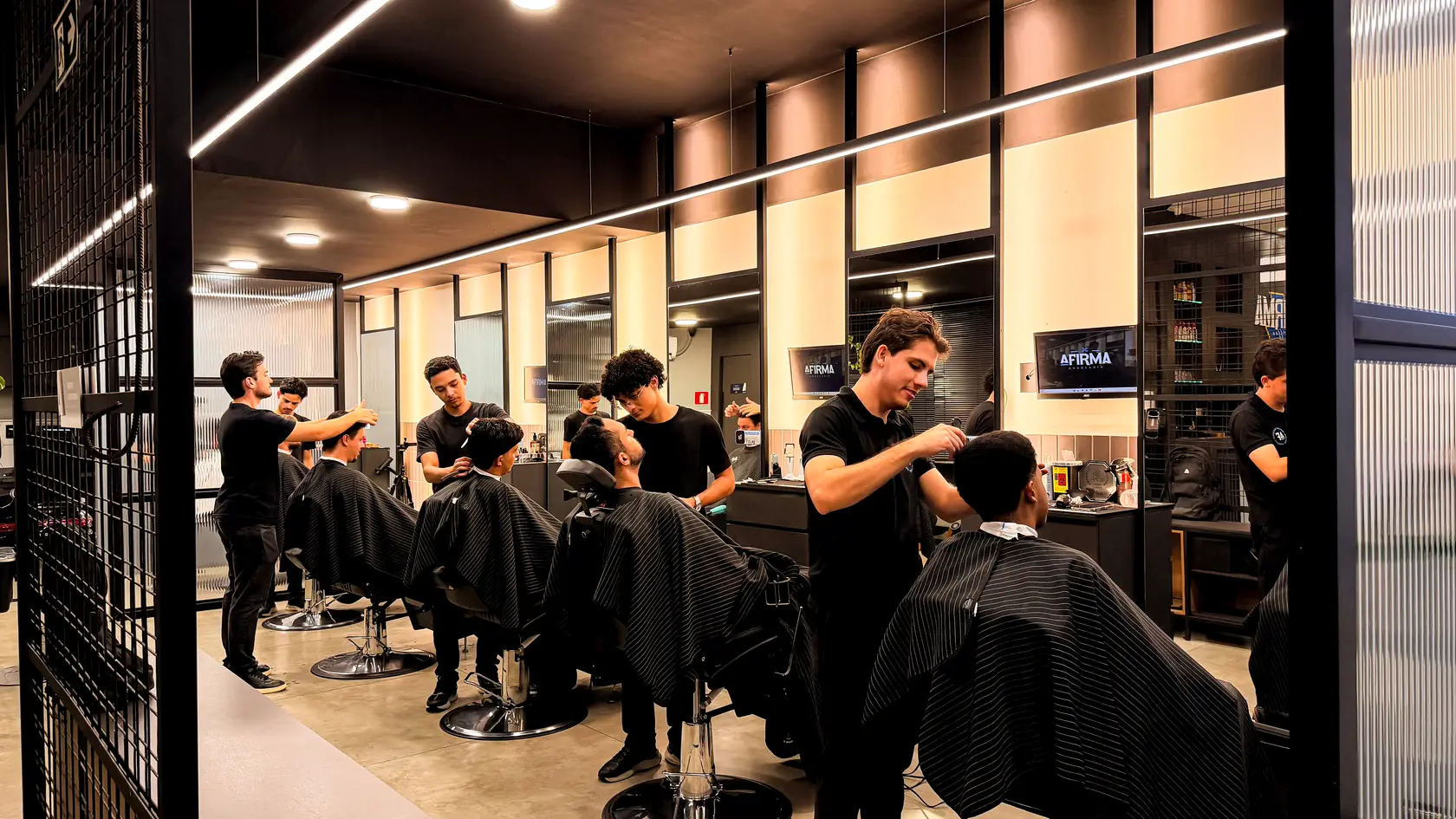 Barbeiros da A Firma Barbearia atendendo clientes no salão