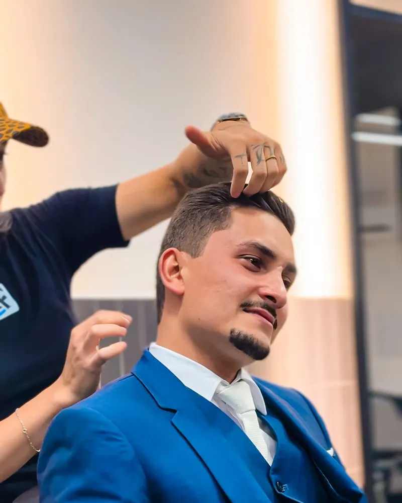 Barbeiro finalizando o penteado do noivo na A Firma Barbearia
