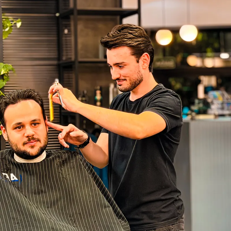 Barbeiro finalizando um corte de cabelo na A Firma Barbearia